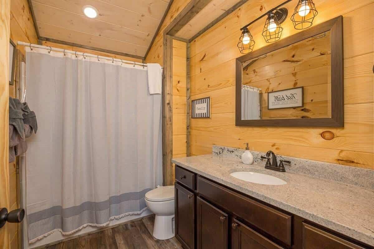 Ein Badezimmer aus Holz mit Duschvorhang, Waschbecken und Spiegel.
