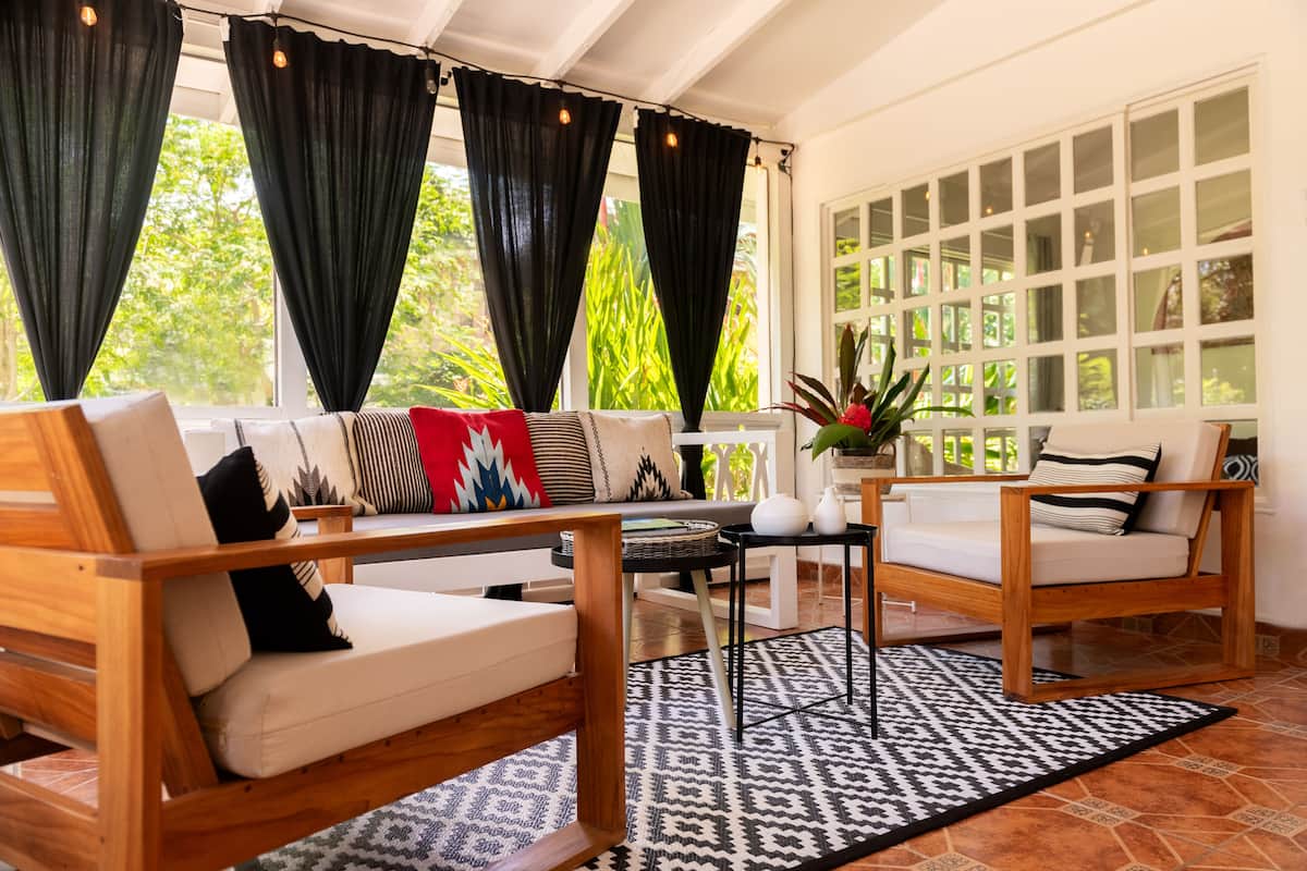 A sunlit room with a wooden sofa set, a small table, and a patterned rug.