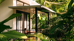 A modern house with a covered patio, surrounded by lush greenery. - La Prometida Hotel (Cahuita)