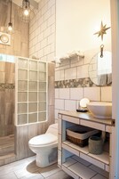 Un baño moderno con ducha, inodoro, lavamanos y espejo.
