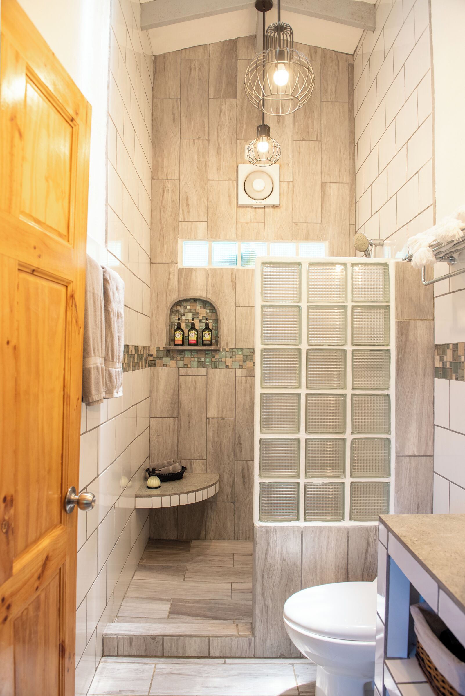 A bathroom with a wooden door, a shower with a glass enclosure, and a toilet.