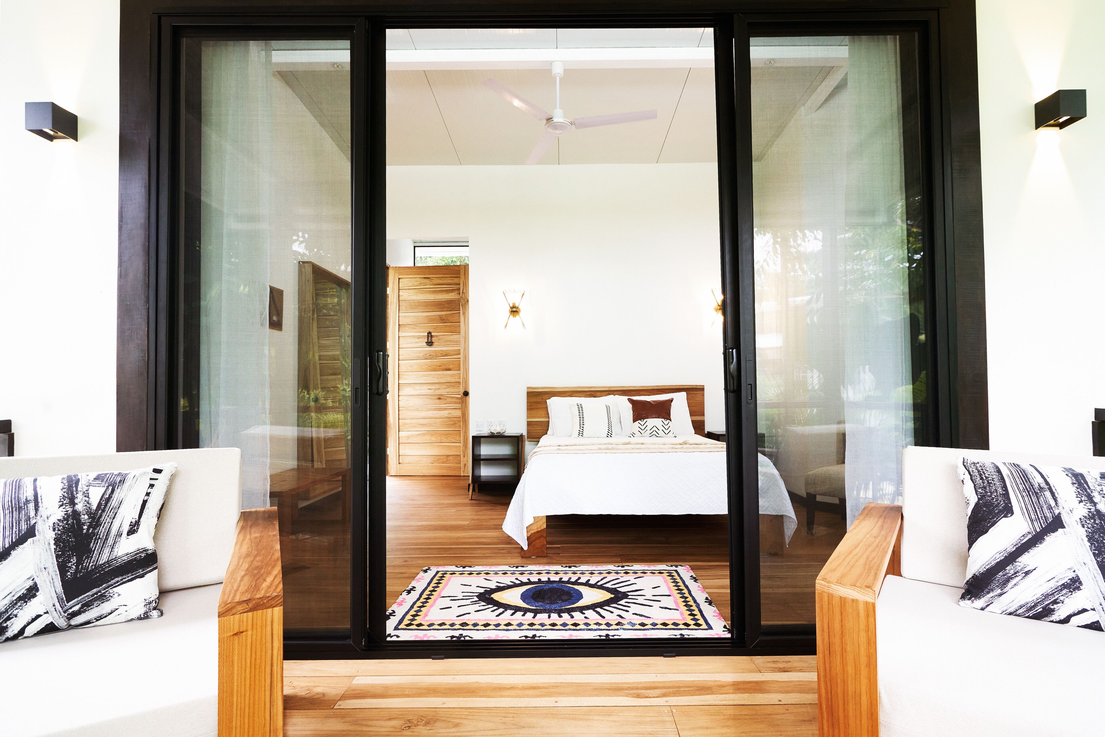 Un dormitorio con cama, suelo de madera, puerta de cristal y vistas al exterior.