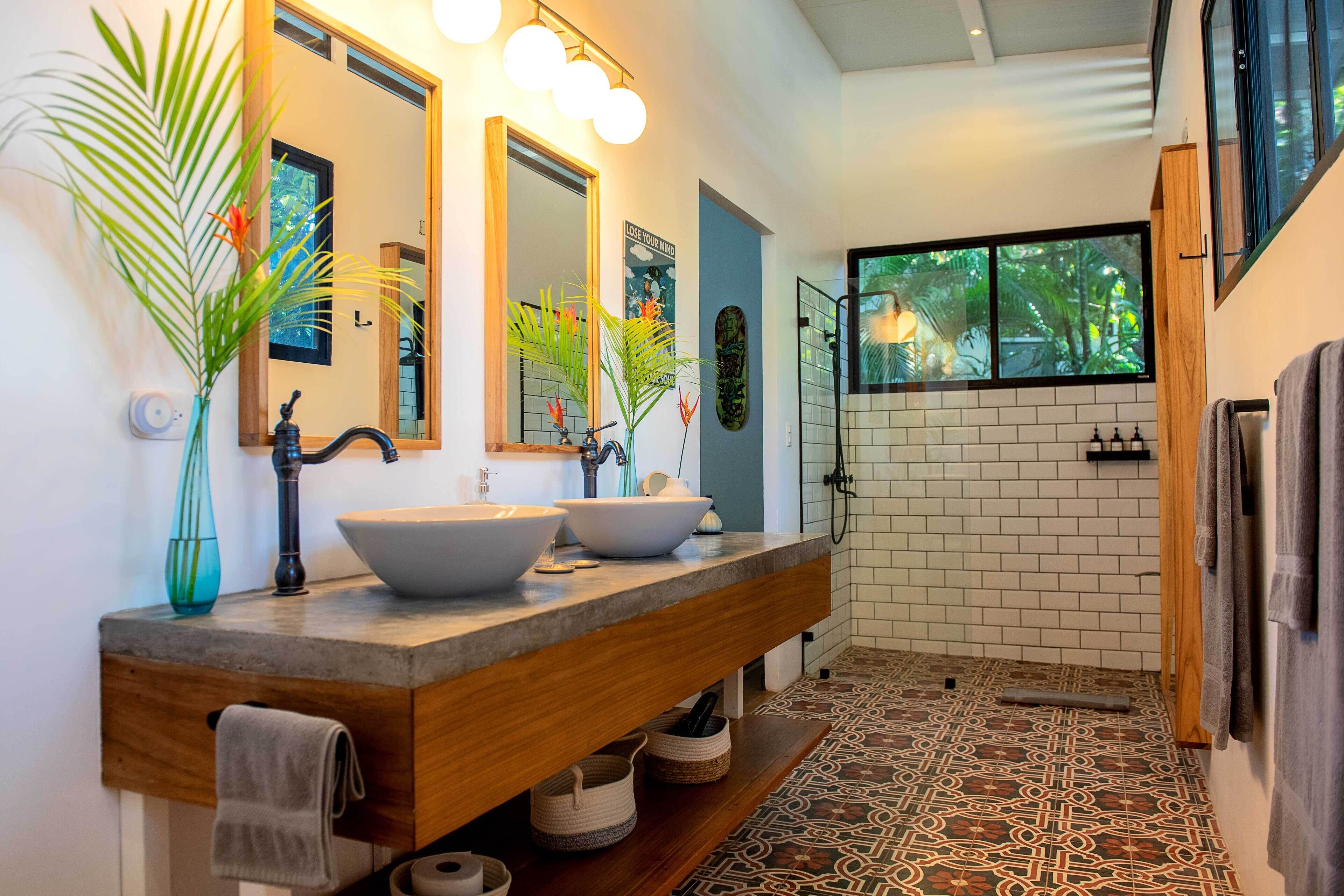 Une salle de bain moderne avec deux grands lavabos, un miroir et un espace douche.