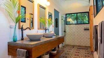 Une salle de bain moderne avec deux grands lavabos, un miroir et un espace douche.