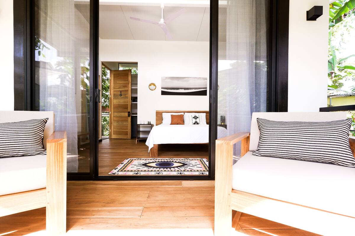 A bedroom with a bed, a ceiling fan, and a view through a glass door.