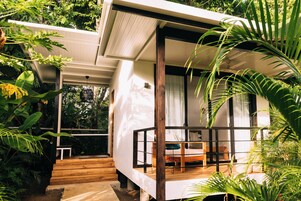 Un dormitorio moderno y amplio, con suelo de madera, ventanas grandes y vistas a vegetación exuberante.