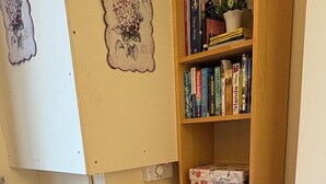 Un petit espace de travail bien aménagé, avec une table en bois, deux chaises noires et une bibliothèque remplie de livres.