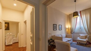 Een goed verlichte woonkamer met een bank, fauteuils en een bijzettafeltje met een plant in pot.