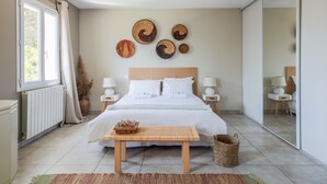 Ein Schlafzimmer mit einem Bett, Nachttischen, einer Holzbank und Wanddekoration.