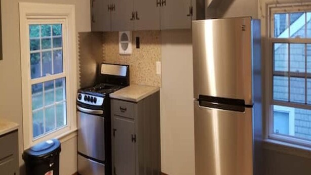 A compact kitchen with a stove, refrigerator, and cabinets.