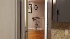 A hallway with a wooden floor, a metal rack, and a framed picture on the wall.