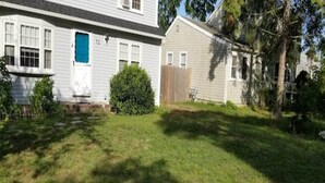 A two-story house with a front yard, a blue door, and a wooden fence.