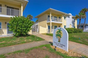 A multi-story hotel with balconies, a palm tree sign, and a well-maintained lawn. - Private 2 bedroom 1 bath with pool, beach, wifi, near Daytona & I-4 to Orlando (Ormond Beach)