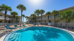 A swimming pool with lounge chairs and palm trees, surrounded by a white fence. - Private 2 bedroom 1 bath with pool, beach, wifi, near Daytona & I-4 to Orlando (Ormond Beach)
