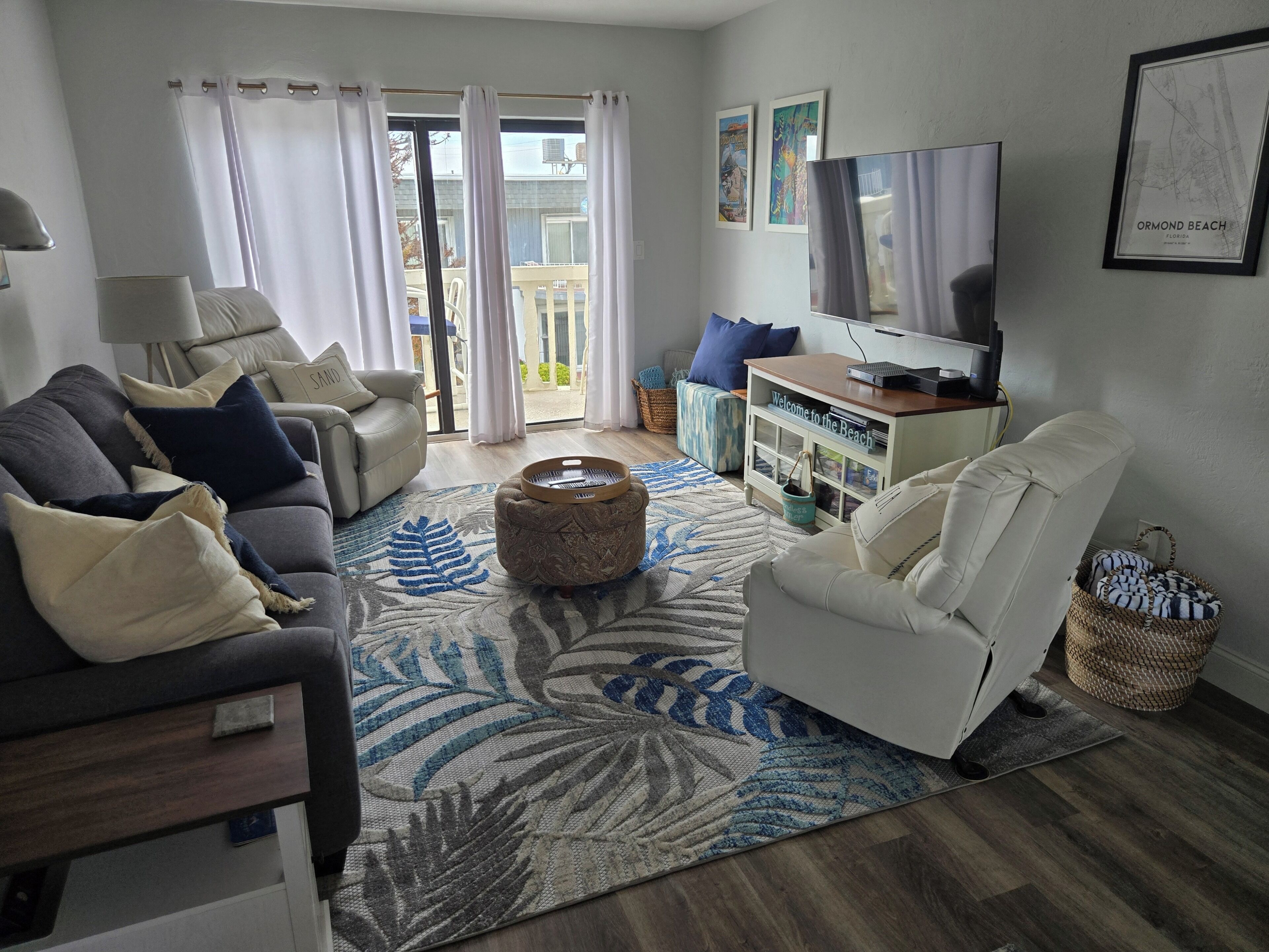 Una sala de estar con sofá, sillón, reposapiés, televisor y una pared decorada con un mapa enmarcado.
