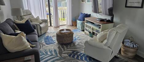 Una sala de estar con sofá, sillón, reposapiés, televisor y una pared decorada con un mapa enmarcado.