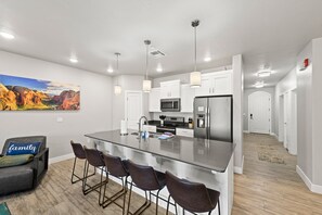A modern kitchen with a central island, stainless steel appliances, and pendant lighting.