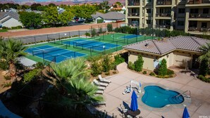 A tennis court, a swimming pool, and a building with balconies. - Bike, Hike, Swim, Explore 5 Star Resort - Guaranteed FUN & Memories (St. George)