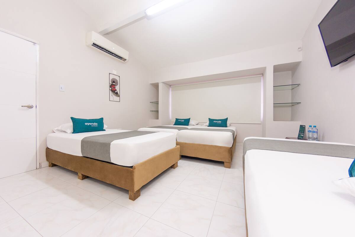 A hotel room with two beds, a flat-screen TV, a window, and a minibar.