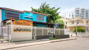 A hostel with a blue facade and a white fence.