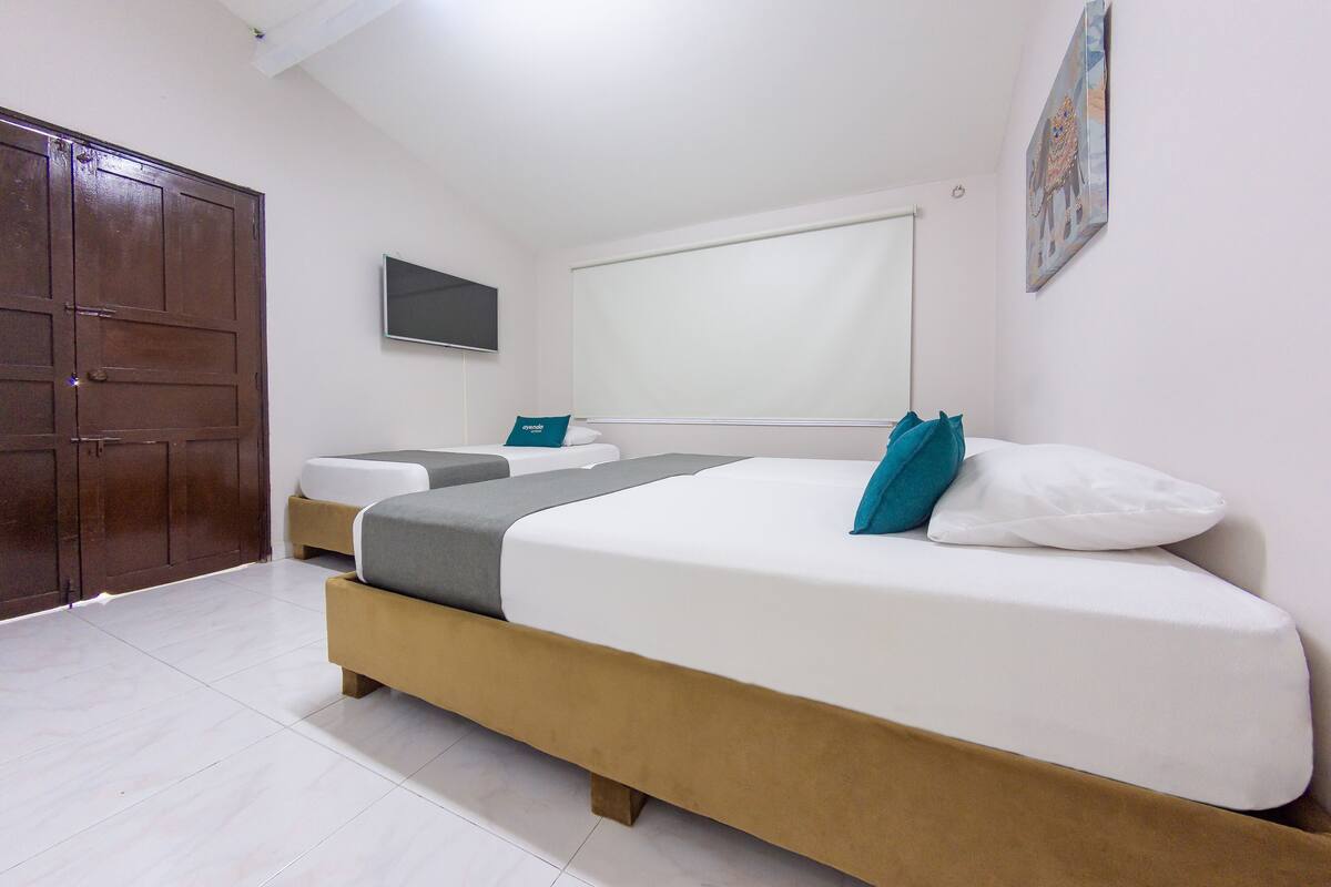 A bedroom with a large bed, a smaller bed, a wardrobe, a television, and a window.