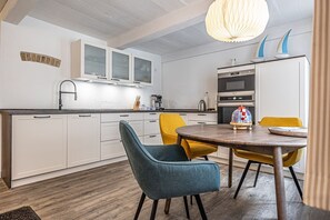 A modern kitchen with white cabinets, a round wooden table, and two chairs.