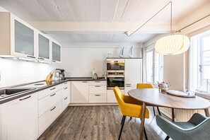 A modern kitchen with white cabinets, a wooden countertop, and a dining area with yellow chairs.