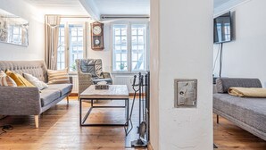 Una sala de estar con un sofá, un sillón y una mesa con un reloj en la pared.