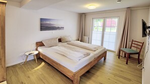 A bedroom with a wooden bed, a bedside table with a lamp, a chair, and a painting on the wall.