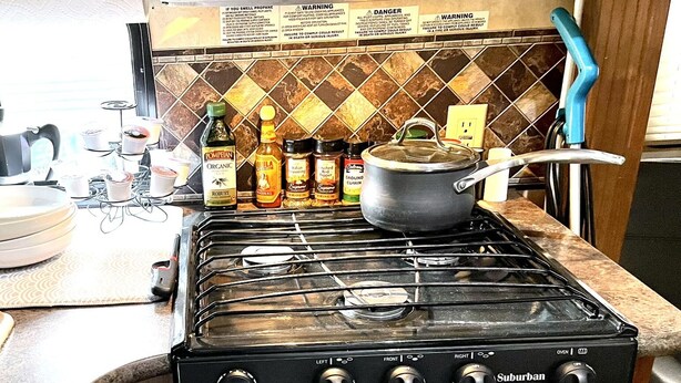 Una cucina con piano cottura a gas, forno e diversi ingredienti per cucinare sul bancone.