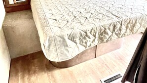 Un letto a castello con materasso trapuntato, una testiera in legno e un piccolo armadio con specchio.
