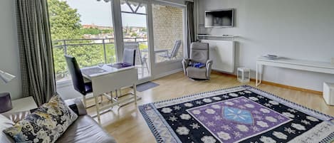 Un salon moderne avec un canapé, une table à manger, un téléviseur et une vue sur la ville.