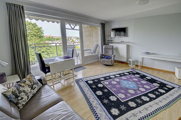 Una sala de estar moderna con un sofá, una mesa de comedor, un televisor y vistas a la ciudad.