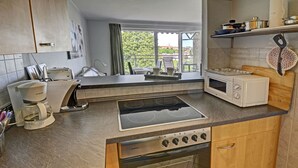 A kitchen with a gas stove, microwave, and coffee maker.