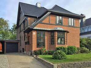 A two-story house with a brick exterior, a garage, and a well-maintained garden.