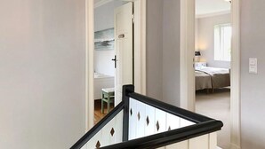 A staircase with a black railing leading to a bedroom with a bed and a nightstand. - fewo1846 - Home port Flensburg - fewo1846 - Home port Flensburg / elegant (Flensburg)