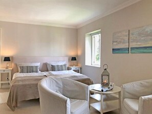 Une chambre avec deux lits, une table de chevet, une table avec une lanterne et une fenêtre.