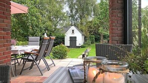 An outdoor patio with a table and chairs, a white building in the background, and a brick wall. - fewo1846 - Home port Flensburg - fewo1846 - Home port Flensburg / elegant (Flensburg)