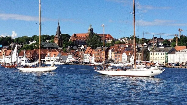A harbor with several sailboats docked, a church steeple, and a row of houses in the background. - fewo1846 - Home port Flensburg - fewo1846 - Home port Flensburg / elegant (Flensburg)
