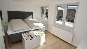 Un dormitorio con cama, mesita de noche, radiador y ventana con vistas al exterior.