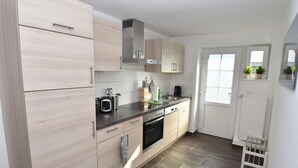 Una cocina moderna con armarios de madera clara, electrodomésticos de acero inoxidable y un ventanal que proporciona luz natural.