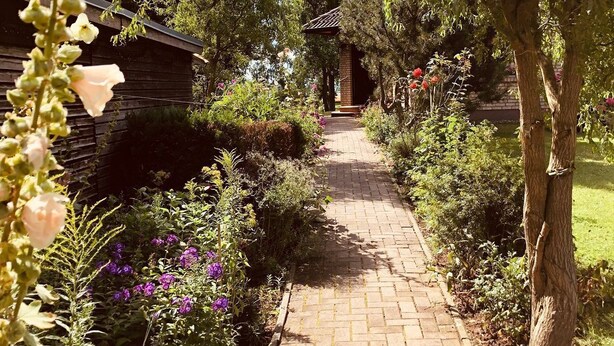 A garden pathway leading to a wooden structure with a tiled roof.