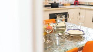 A dining table with a pitcher, glasses, and plates, set in a kitchen with patterned tiles and a red appliance.