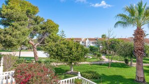 A well-maintained garden with various trees and a clear blue sky. - Top Apartment with Sea View and Pool (el Gran Alacant)