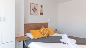 A neatly arranged hotel room with a bed, a wooden nightstand, and a wall-mounted light fixture. - Top Apartment with Sea View and Pool (el Gran Alacant)