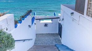 A staircase leading to a balcony overlooking the sea, with potted plants and a logo on the wall. - Magnífica duplex renovado con piscina garaje y jardín, frente a la playa de... (Los Caños de Meca)