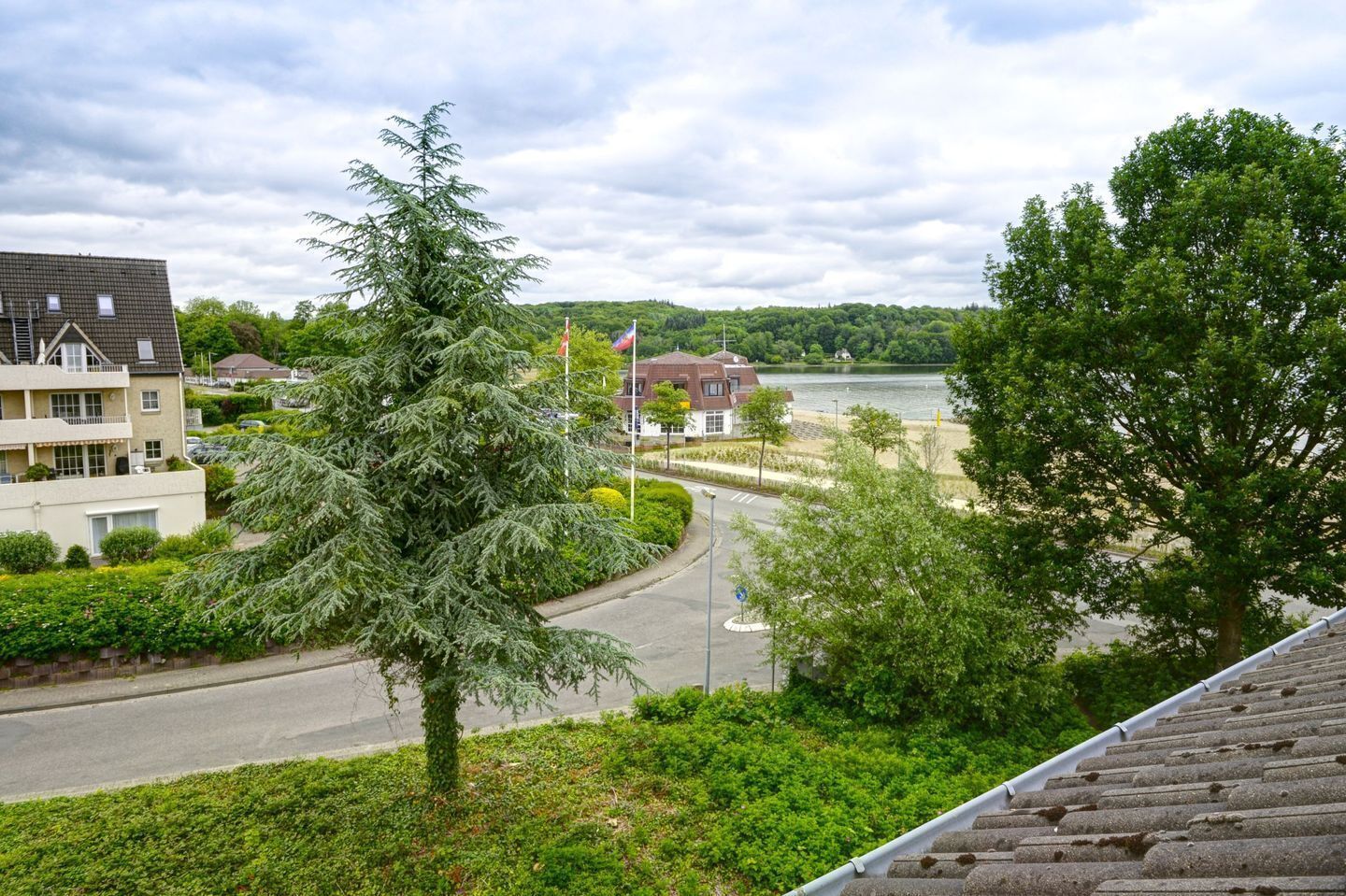 Ett bostadsområde med en väg som slingrar sig runt en sjö, omgivet av hus och grönområden.