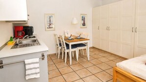 A compact kitchen with a dining area, a coffee machine, and a single bed. - fewo1846 - Little Mermaid (App. 666) / Studio apartment on the top floor - (Harrislee)