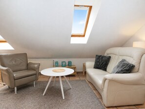 A modern living room with a high ceiling, a skylight, a beige sofa, a white coffee table, and a grey rug. - fewo1846 - Little Mermaid (App. 666) / Studio apartment on the top floor - (Harrislee)