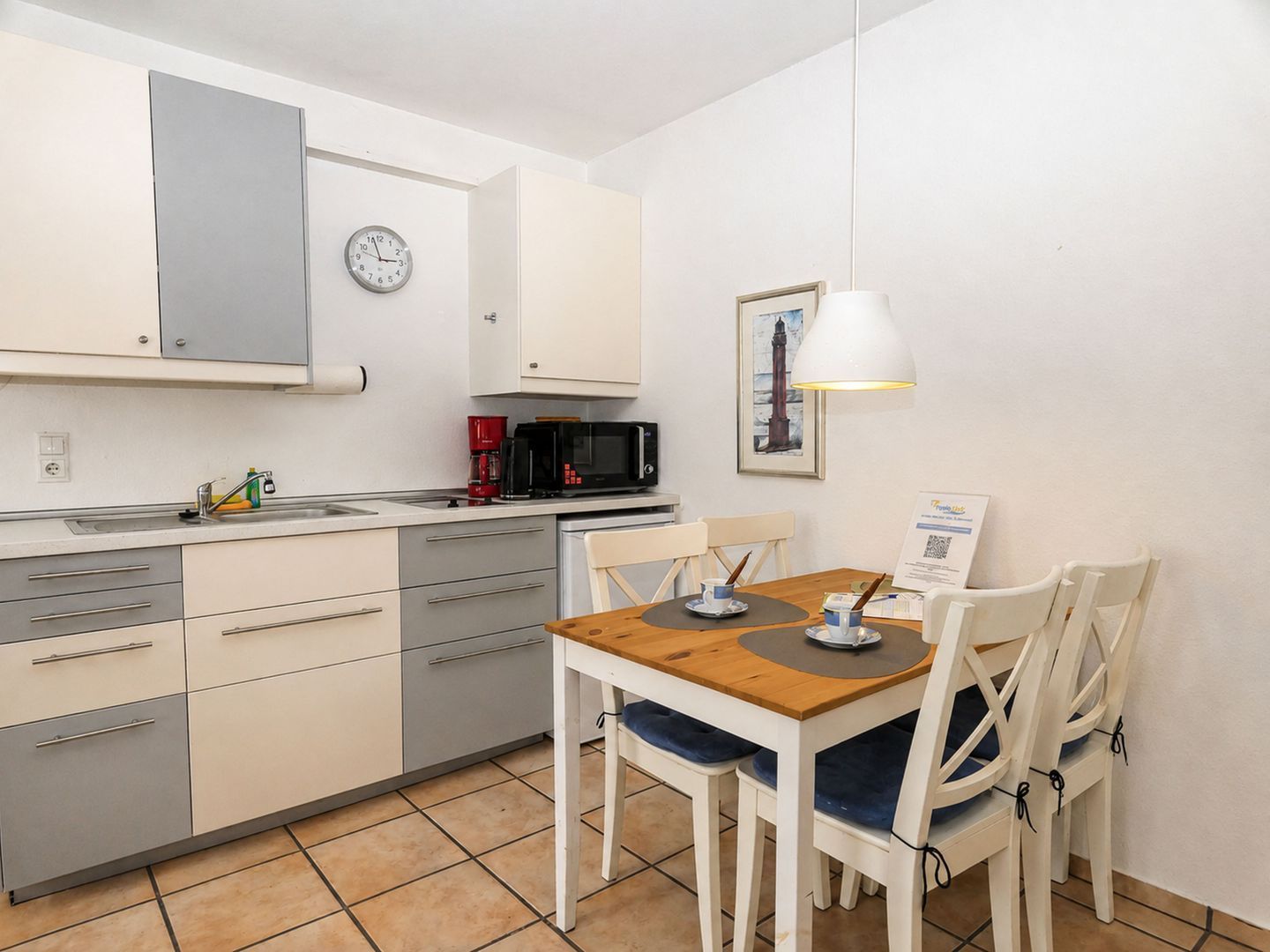 A compact kitchen with a microwave, coffee maker, and a clock on the wall.